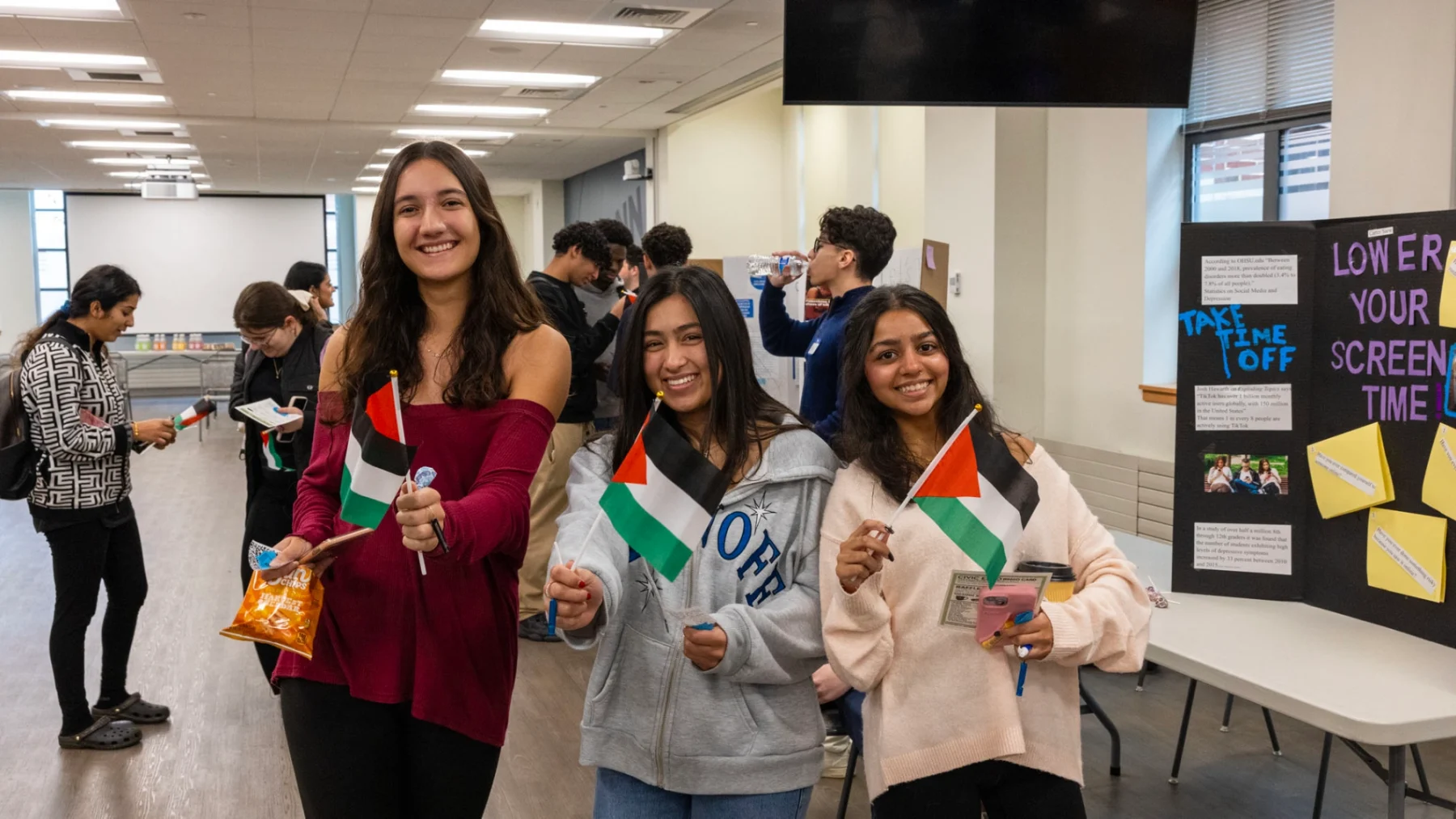 Three female students holding the Palestinian flags posing for photo.